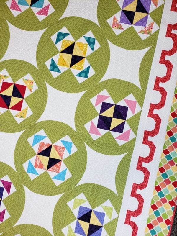 A close up of the quilt pattern on a green background
