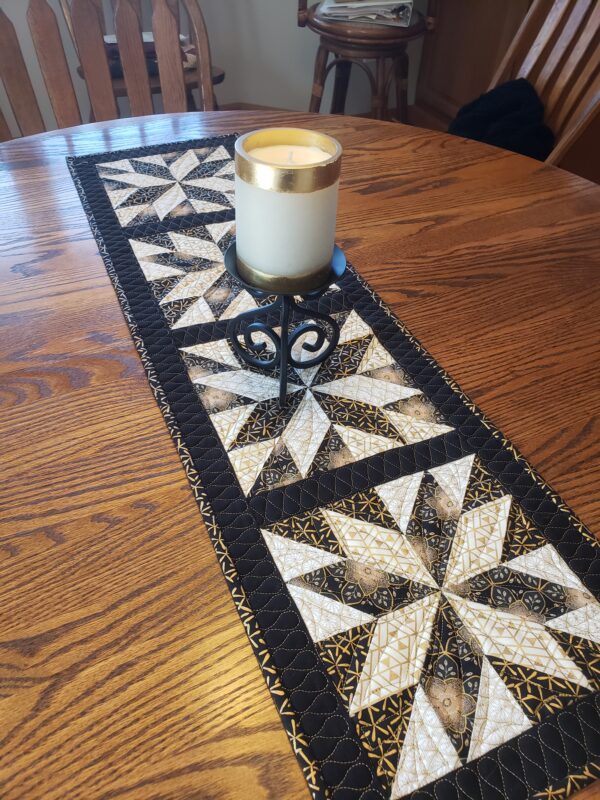 A table with a candle and a quilted table runner.